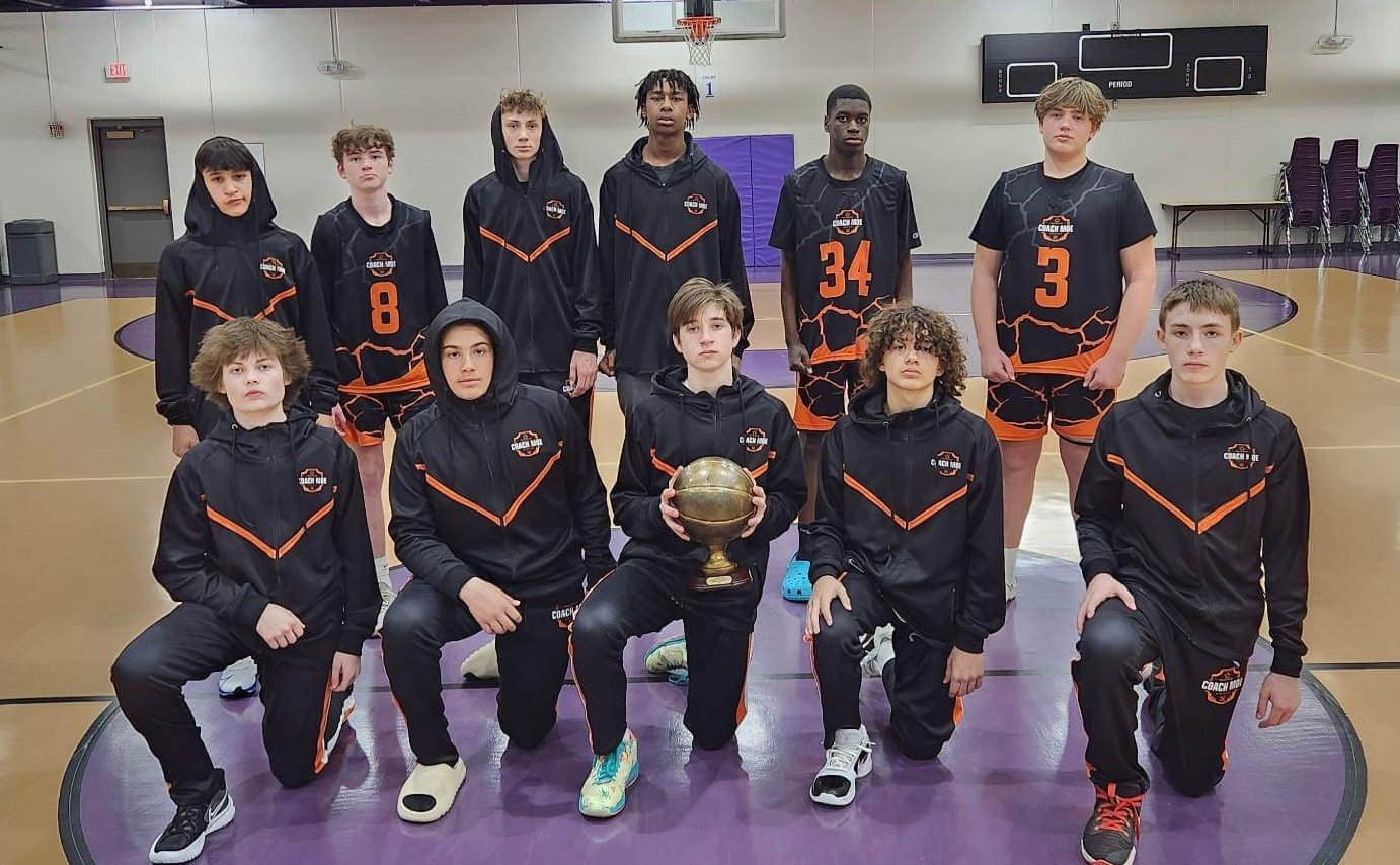 Teen boys basketball team in custom black and orange Capra warmups holding a trophy