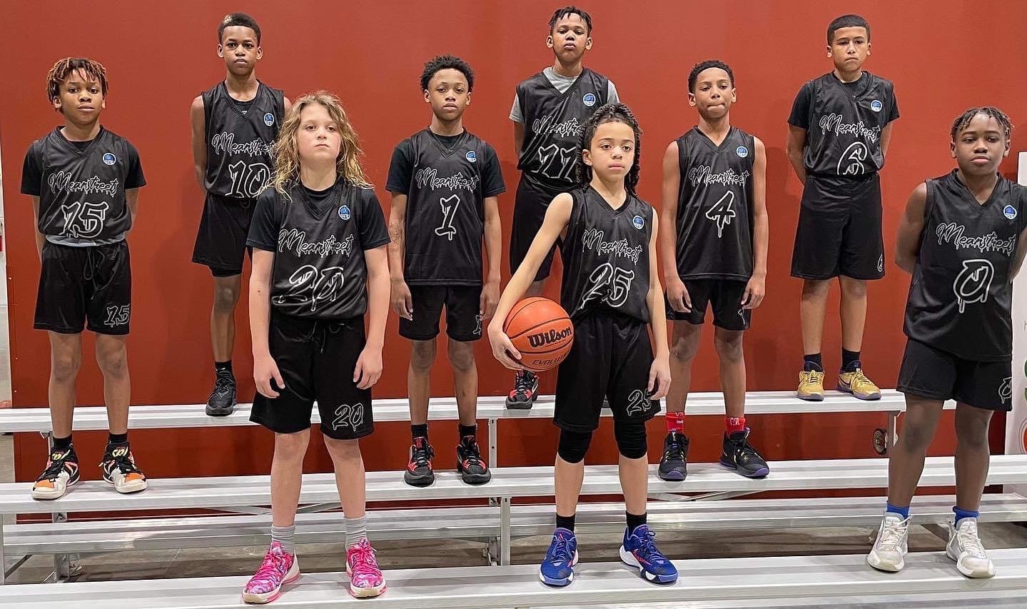 Youth boys basketball team in custom black Capra uniforms holding a basketball