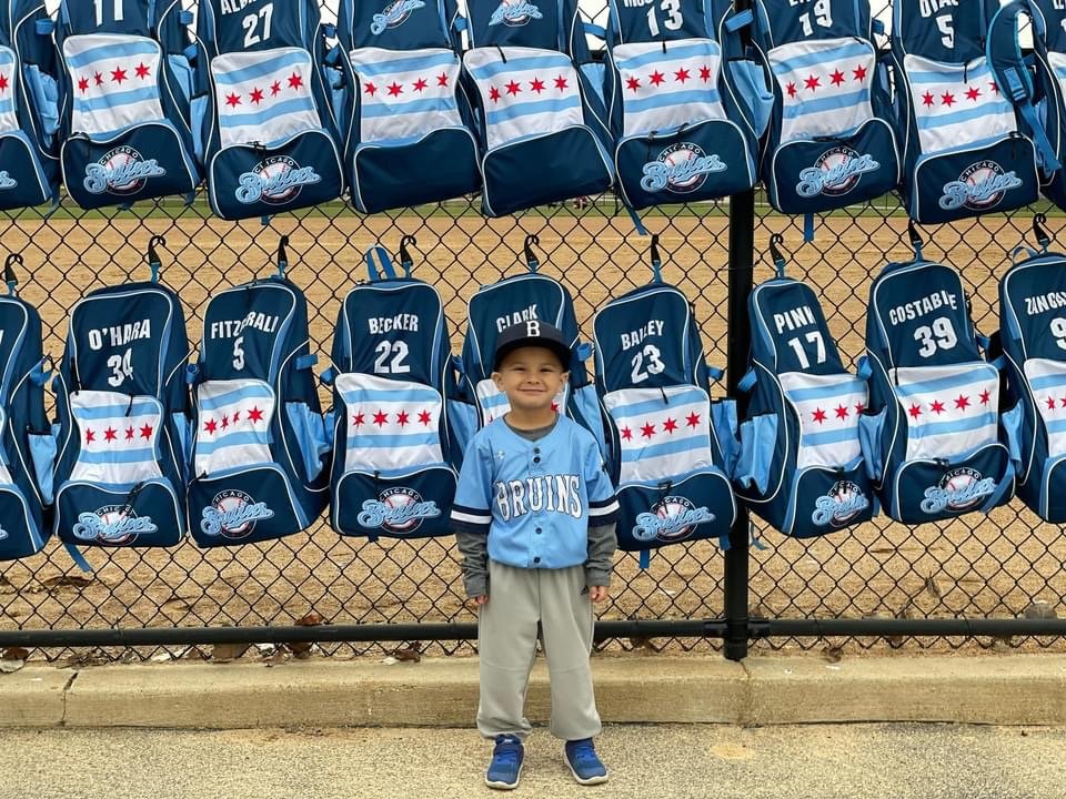 Young Bruins fan in a custom Capra baseball jersey in front of the team's jerseys