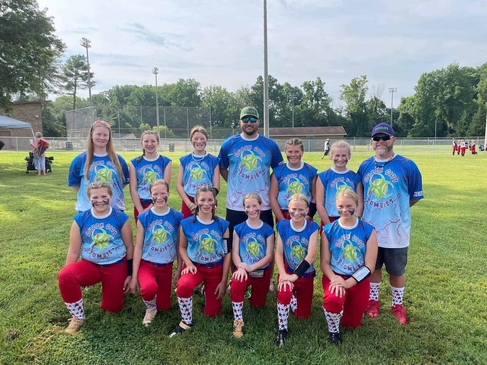 Youth softball team in custom blue Capra shirts and red pants on the field