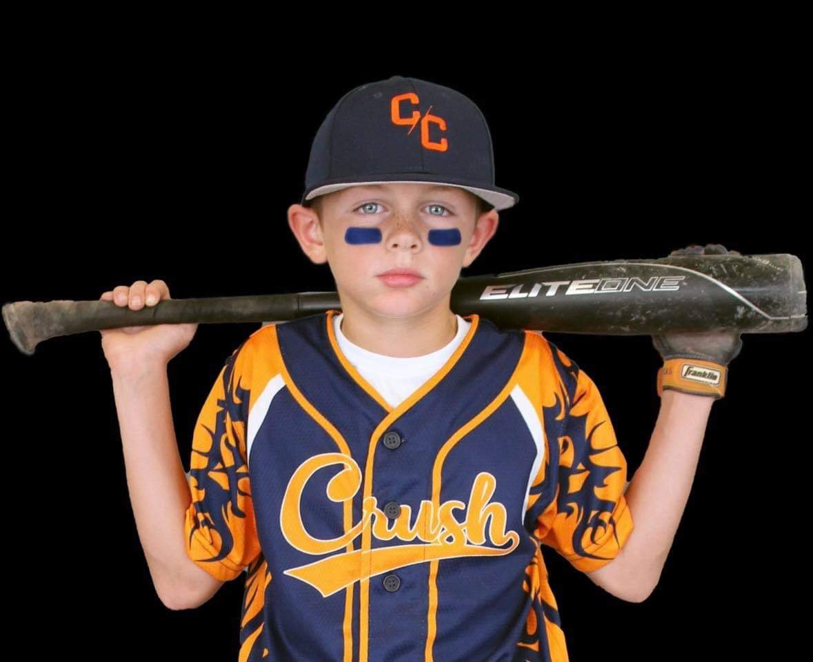 Youth baseball player in a custom navy and orange Crush sublimated Capra jersey