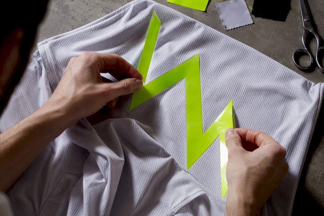 Hands placing vinyl HTV on dark jersey fabric